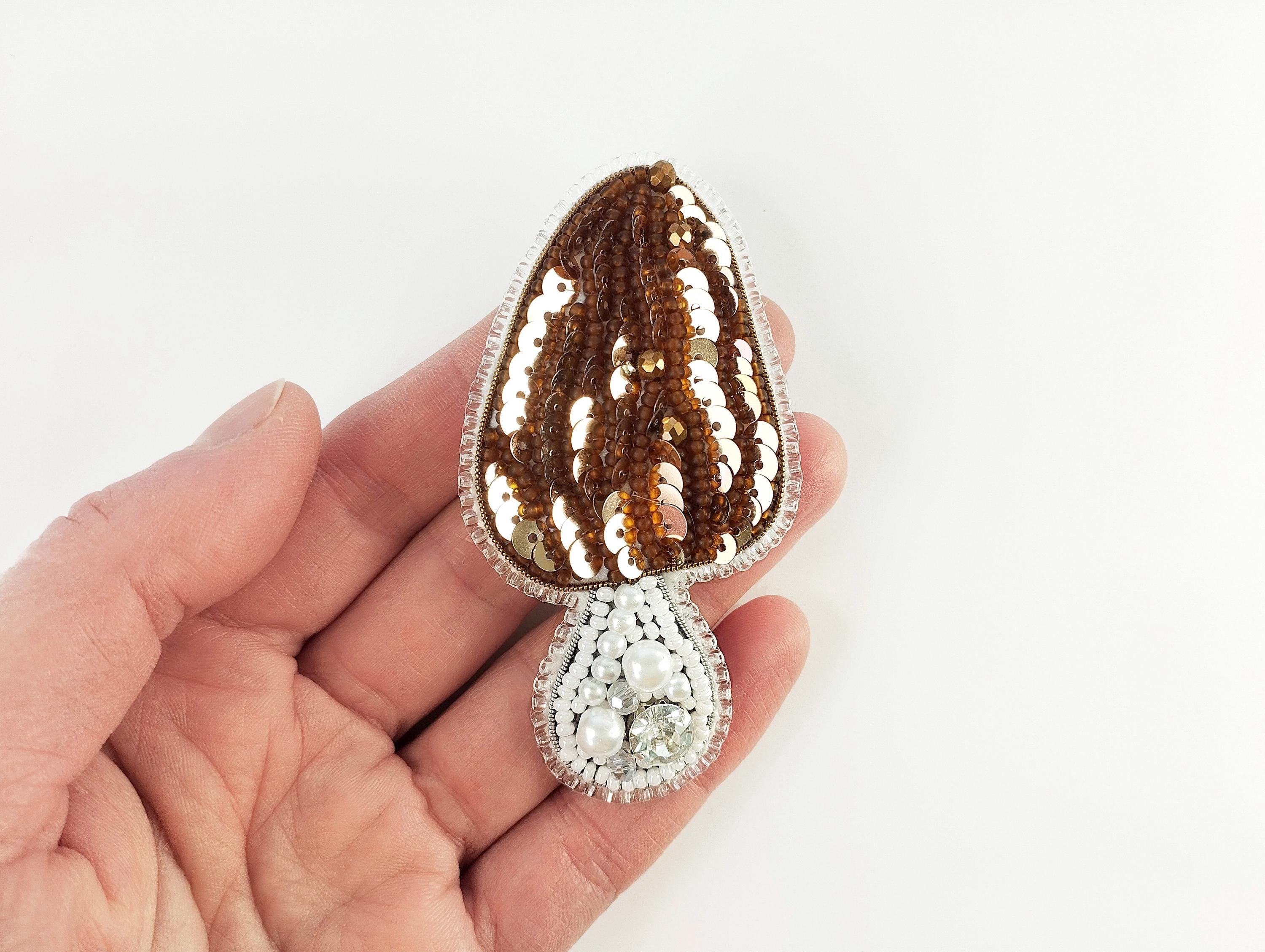 a hand holding a brown and white brooch